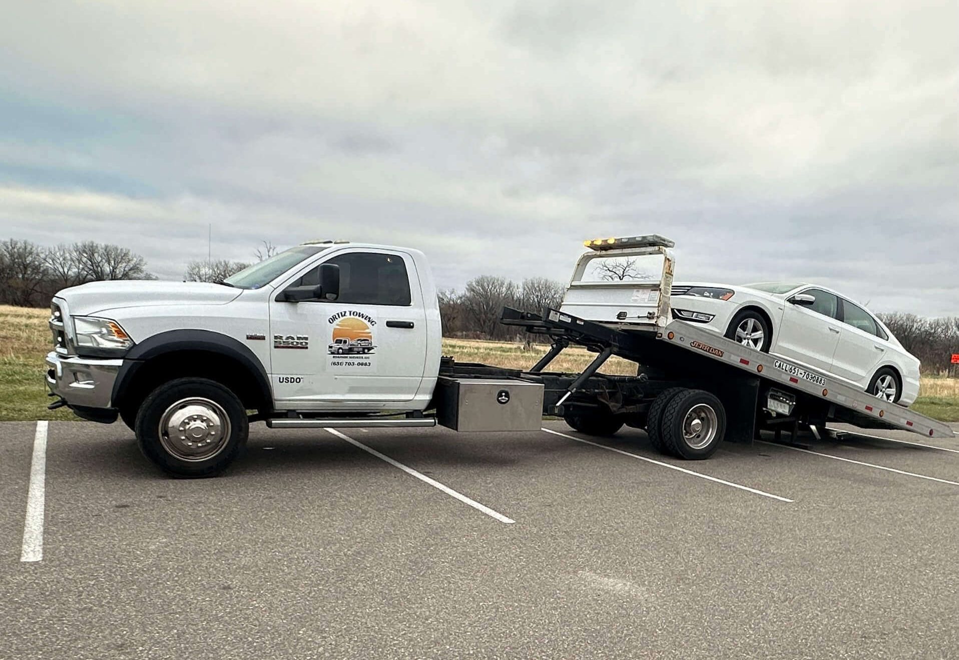 A flatbed tow truck safely transporting a luxury car.