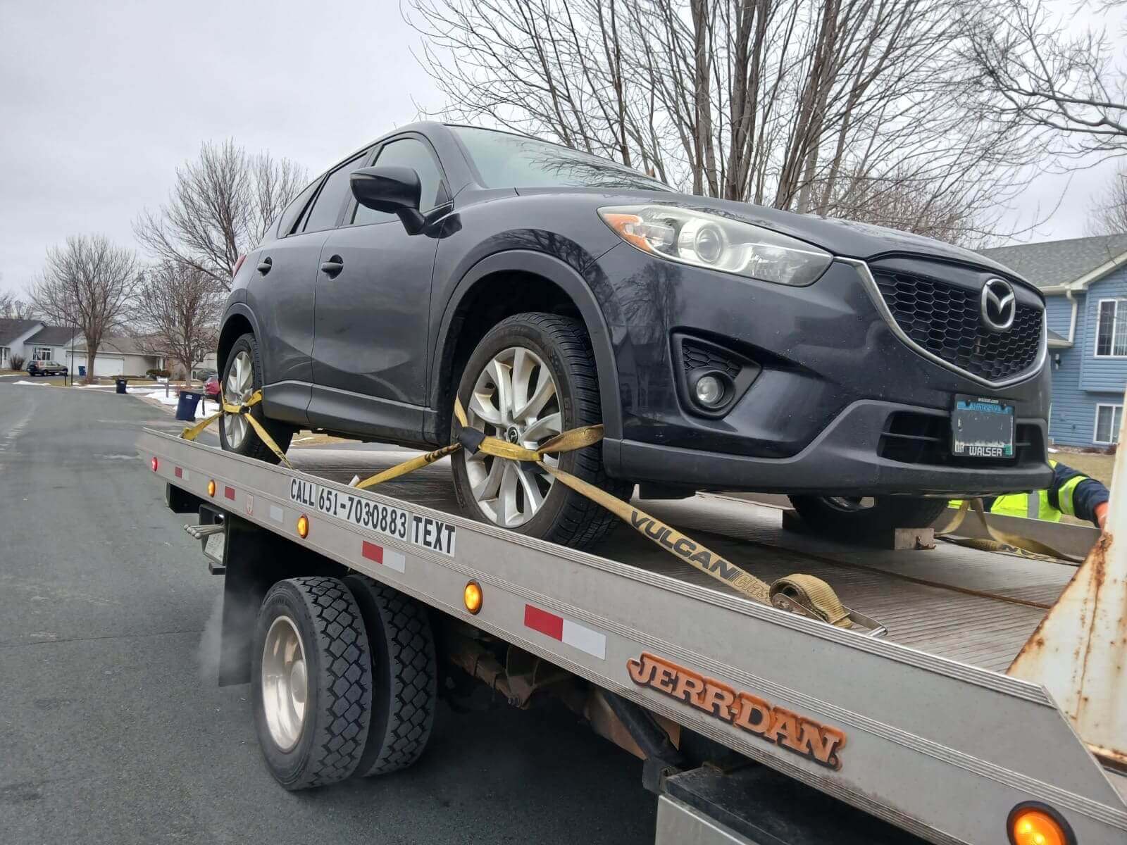 A heavy-duty tow truck towing a large SUV.